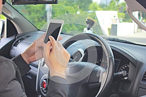 Man using mobile smart phone, typing message or checking newsfeed on social networks in the car