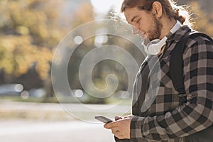 Man using mobile smart phone. Young man texting on his smartphone in the city. Close up of cheerful adult using mobile