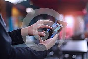 Man using mobile smartphone for online banking in cafeteria