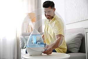 Man using modern air humidifier at home