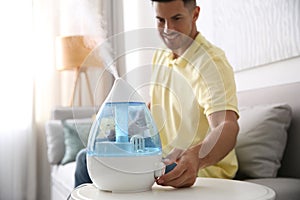 Man using modern air humidifier at home