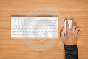 Man using mouse and keyboard on wooden table. top view