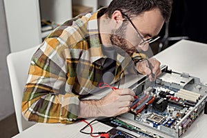 man using multimeter while fixing computer
