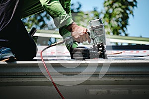 Man using a nail gun on the roof