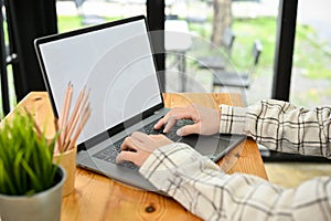 A man using notebook laptop computer, typing on keyboard. Laptop white screen mockup
