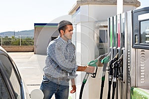 Man using nozzle to refuel his car in gas station