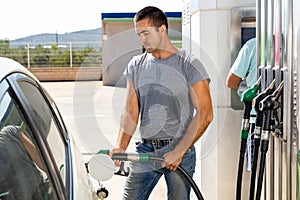 Man using nozzle to refuel his car in gas station