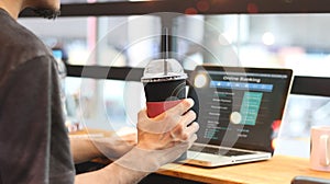 Man using online banking on laptop screen device in coffee shop.