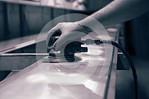 Man using orbital sander to prepare a metal panel.