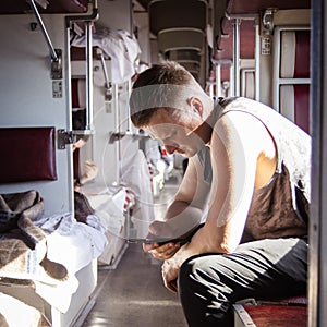 a man using a phone in the aisle of a second-class carriage of a high-speed train waiting for his stop, the background is blurred