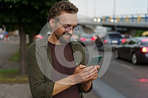 Man using phone on evening city street, presumably to call taxi cab driver. soft evening lighting adds touch of ambiance photo