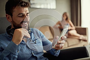 Man using phone while sitting on sofa at his modern home. Concept of young people working mobile devices