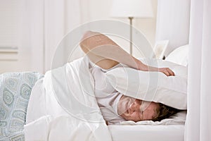 Man using pillow to block out noise