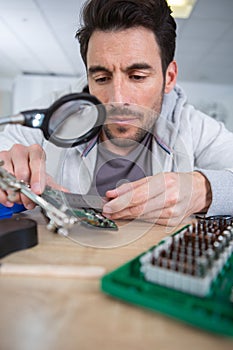 man using plier to assemble printed circuit board