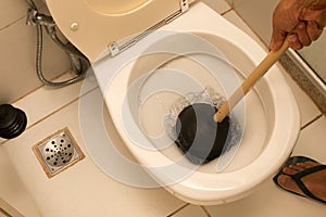 Man Using Plunger to unstop his toilet