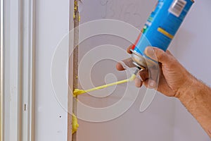 Man using polyurethane foam for installing a window on a handsome worker in action