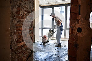 Man using power trowel machine at construction site.