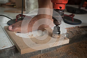 A man using powered drill with a hole saw bit to make precision hole in a wooden plank.
