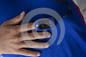 A man using pulse oximeter used to measure pulse rate and oxygen levels at home.