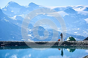 Man using radio near tent in mountains.