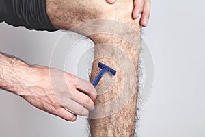 Man using razor to remove hair on leg