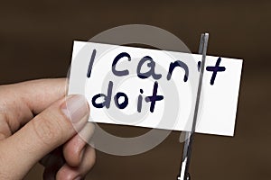Man using scissors to remove the word can`t to read I can do it