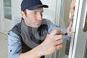 Man using screwdriver to adjust door hinge