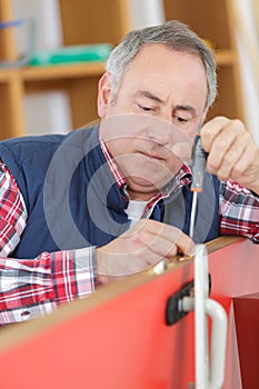 Man using screwdriver to adjust door hinge