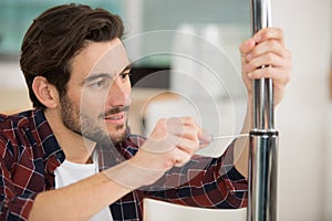 man using screwdriver to secure seal between two metal tubes photo