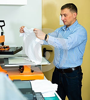 Man using a serigraph press to print a shirt in a workshop