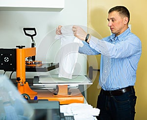 Man using a serigraph press to print a shirt in a workshop