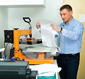 Man using a serigraph press to print a shirt in a workshop