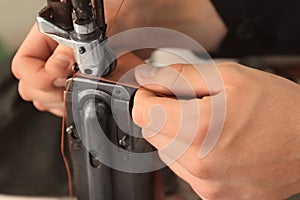 Man using sewing machine in leather workshop, closeup