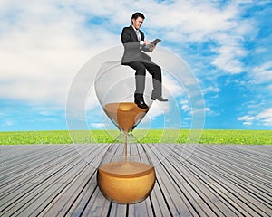 Man using smart pad sitting on sandglass