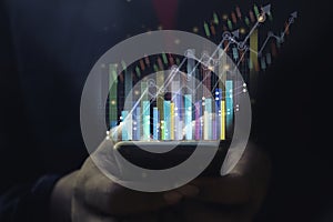 A man using smart phone analyzing graph for data management to make report.