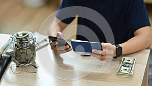 Man using smart phone, calculating money bank loan rent payments, managing expenses finances in living room