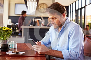 Man using smart phone in a coffee shop