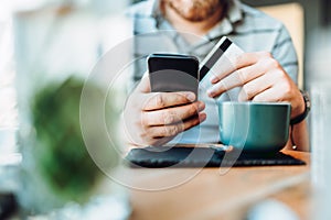 Man using smart phone and credit card in local cafe. shopping online with credit card