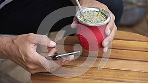 Man using smart phone and drinking yerba mate tea. Slow Motion.