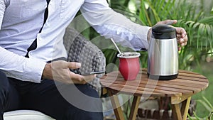 Man using smart phone and drinking yerba mate tea. Slow Motion.