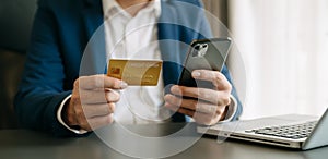 Man using smart phone for mobile payments online shopping,omni channel,sitting on table,virtual icons graphics interface screen