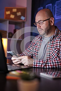 Man using smart phone while working late