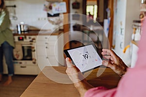 Man using smart thermostat, adjusting, lowering heating temperature at home. Concept of sustainable, efficient, and