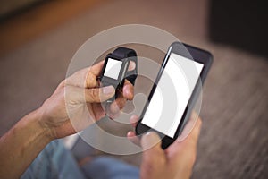 Man using smart watch and mobile phone in living room