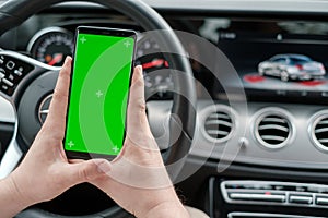 Man using smartphone on the background of a luxury class car dashboard