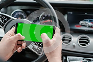 Man using smartphone on the background of a luxury class car dashboard