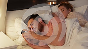 Man using smartphone while girlfriend is sleeping