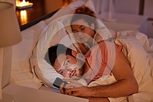 Man using smartphone while girlfriend is sleeping