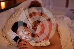 Man using smartphone while girlfriend is sleeping