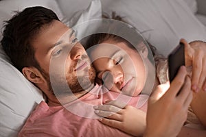 Man using smartphone while girlfriend is sleeping